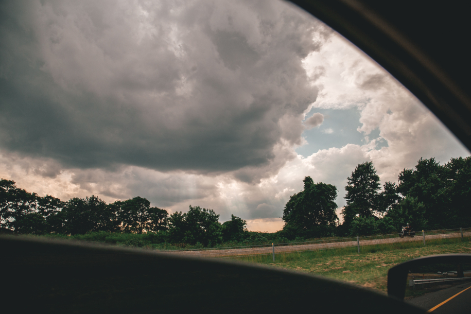 A beautiful shot of cloudy skies above trees taken from a car