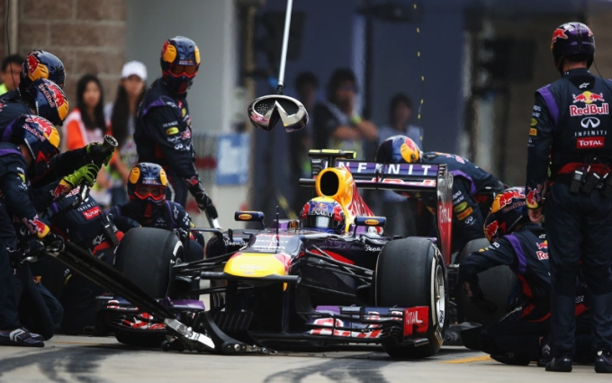 Red-Bull-F1-race-car-in-pit-for-tire-change-with-pit-crew-in-motion