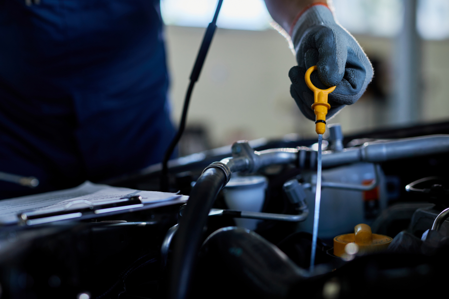 Close-up of a mechanic checking car oil in auto repair shop.