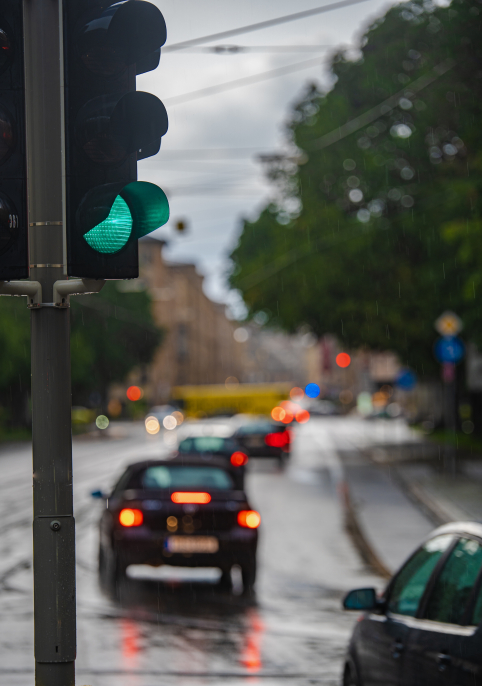 Green traffic light during the rain. Cars drive by, brake lights come on and reflect from the wet road. Concept for car rides in Munich, Germany.