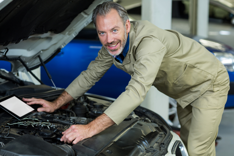 Mechanic servicing automobile car engine in repair garage