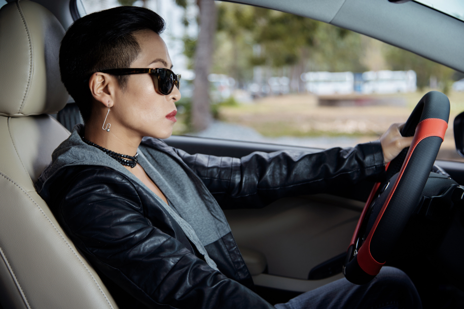 Cool woman in sunglasses and leather jacket driving car